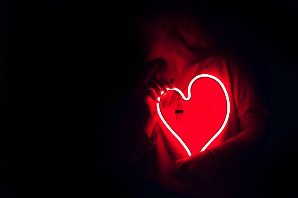 pexels-photo-887349 Silhouette of a person with a glowing red neon heart in the dark, symbolizing love.